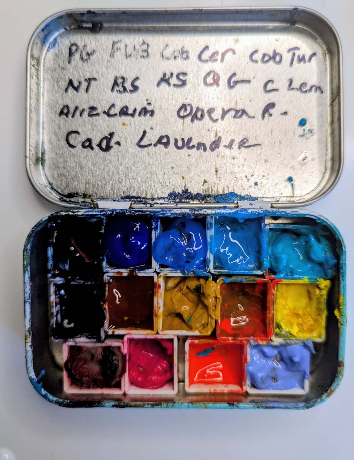 My opened mint-tin watercolor palette filled with fourteen tube colors in small pans